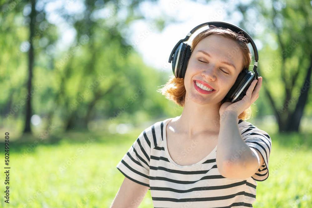 Young woman happens to have music in a summer park Young woman happens to have music in a summer park