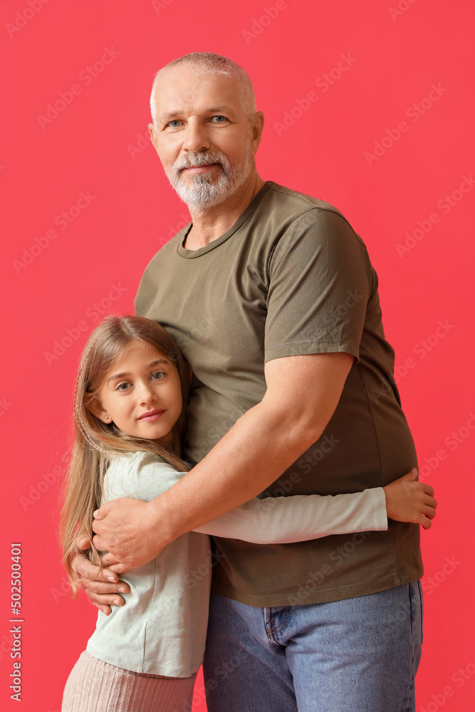 Little girl with her grandfather hugging on red background Little girl with her grandfather hugging on red background