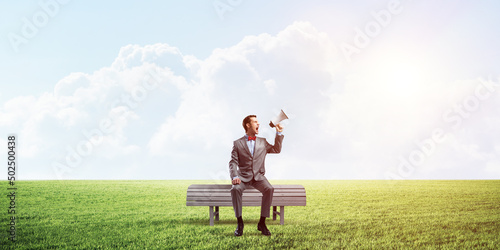 Businessman in summer park announcing something in loudspeaker