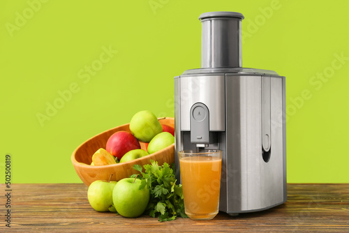 Fototapeta Naklejka Na Ścianę i Meble -  New modern juicer and glass of fresh juice with fruits on wooden table