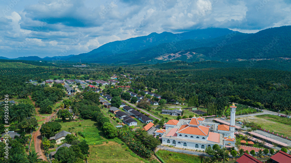 Aerial drone view of Tun Khalil Mosque with mountain background at Asahan, Melaka, Malaysia.