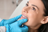 Beautiful woman with dental braces visiting dentist in clinic, closeup