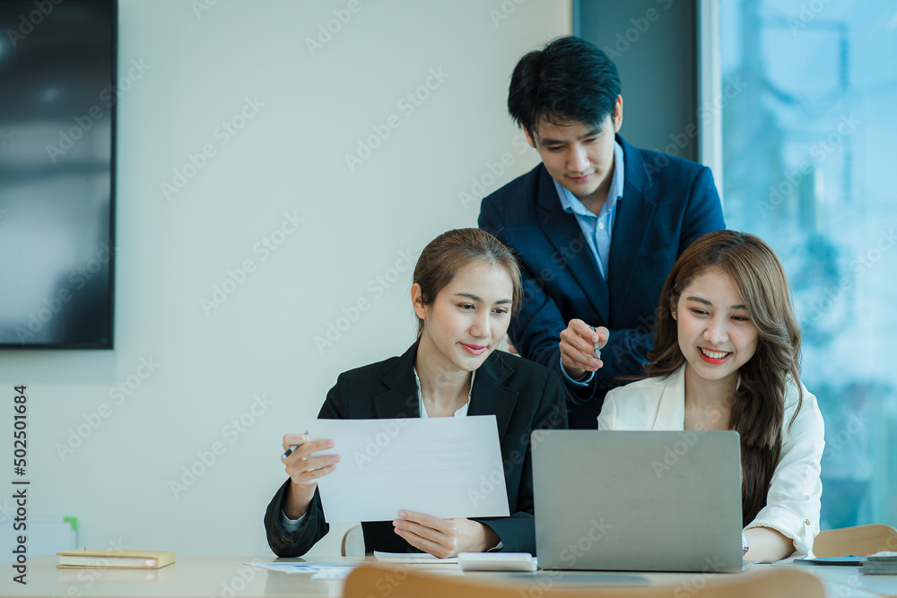 A group of young Asian businessmen working as a team brainstorm, analyze a financial chart, or discuss a marketing plan. Women leaders present and plan new business strategies. teamwork concept A group of young Asian businessmen working as a team brainstorm, analyze a financial chart, or discuss a marketing plan. Women leaders present and plan new business strategies. teamwork concept