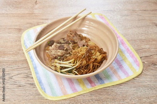 dry Chinese yellow egg noodles dressing black soy sauce topping braised pork on bowl photo