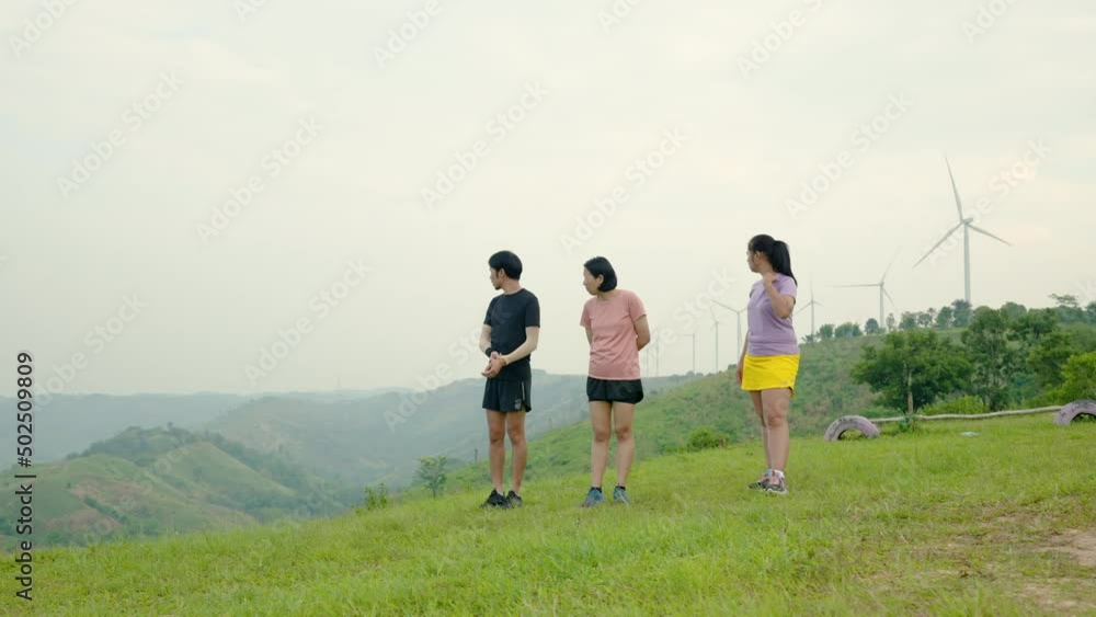 4K 50fps, Three Asian trail runners, standing chatting and looking at the high mountains to relieve fatigue, after the trial run, on a cool morning. 4K 50fps, Three Asian trail runners, standing chatting and looking at the high mountains to relieve fatigue, after the trial run, on a cool morning.