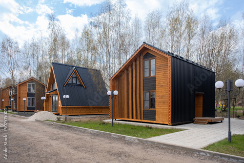 A group of houses in the same style. Trendy modern barnhouse style houses. bright blue sky