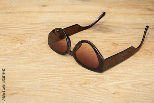 Black sunglasses on the table. Wooden table with beautiful texture