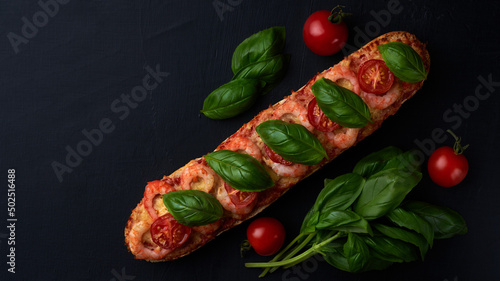 Homemade baguette sandwich or pizza with shrimp, cherry tomatoes and fresh basil leaves on top. Top view photo on a dark background with place for your text.