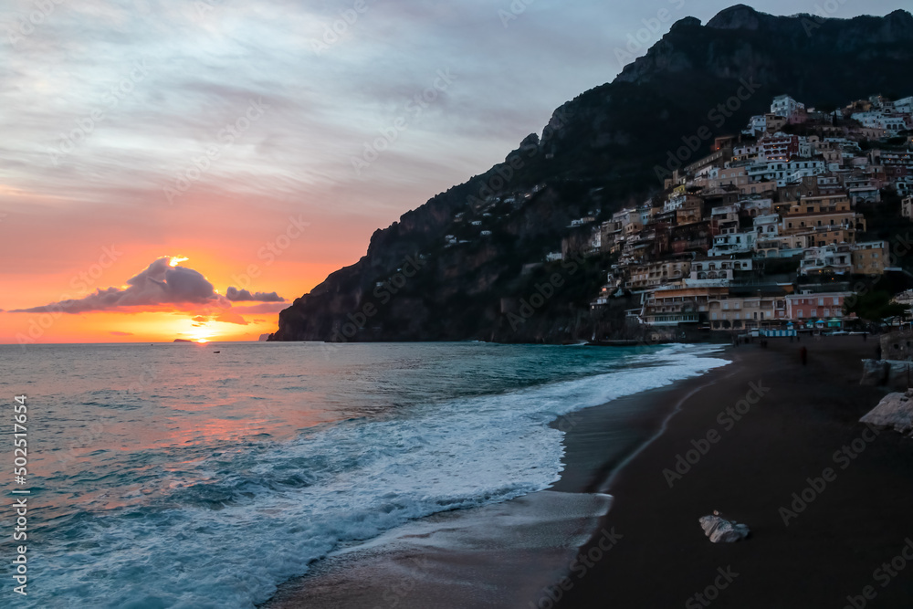 Panoramic sunset view on sandy Fornillo Beach and colorful buildings of hillside village Positano at Amalfi Coast, Italy, Campania, Europe. Luxury vacation at Tyrrhenian, Mediterranean Sea. Coastline