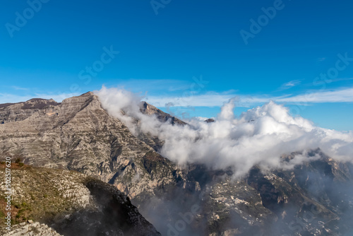 Panoramic view from Monte Comune on cloud covered peaks of Monte Molare, Canino, Caldare, Lattari Mountains, Apennines, Amalfi Coast, Italy, Europe. Hiking trail going to coastal town Positano at sea © Chris