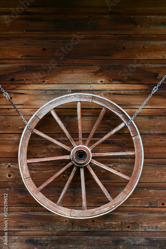 drewniane koło od wozu na tle starych drewnianych desek. idealne jako tło na pulpit lub tekstura © fotolowkey