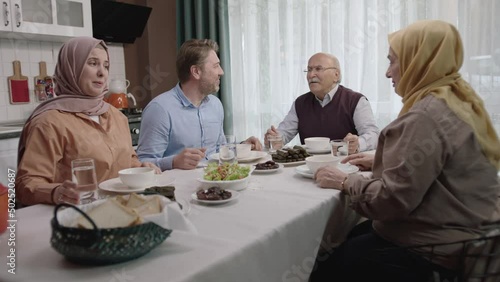 Happy Muslim family having iftar dinner together in the kitchen.A Muslim Turkish family breaks their fast at the iftar table. Iftar is the evening meal at which Muslims end their daily Ramadan fast.