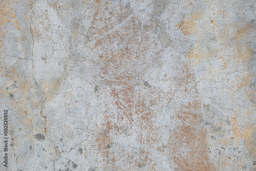 Old gray and white concrete wall with cracks and rust colored stains grunge background texture