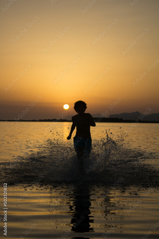 Natural reserve of the Stagnone or natural reserve of the Saline
dello Stagnone near Marsala and Trapani, Sicily, Italy,
silhouette of person moving in the shallow water at sunset