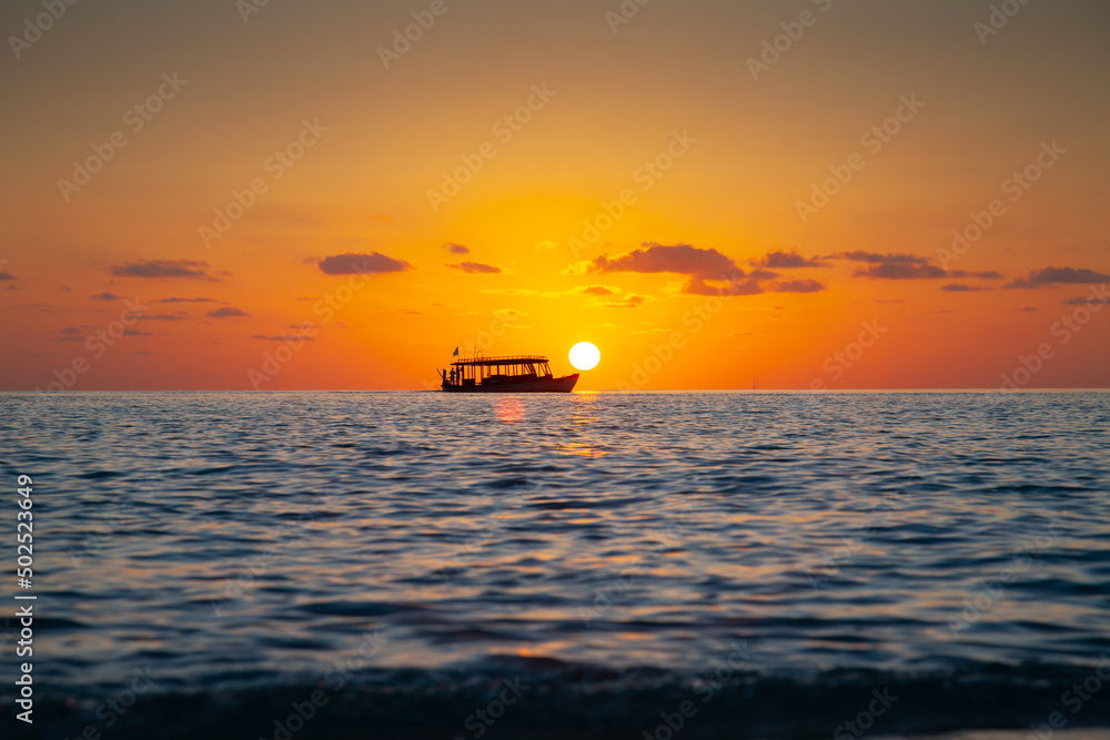 Tourist Boat on Horizon Line at Sunset in the Maldives