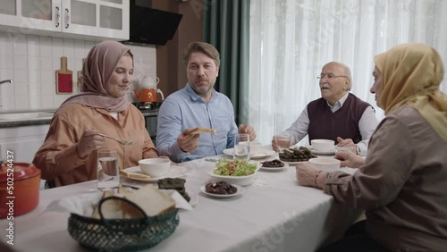 Happy Muslim family having iftar dinner together in the kitchen.A Muslim Turkish family breaks their fast at the iftar table. Iftar is the evening meal at which Muslims end their daily Ramadan fast.
