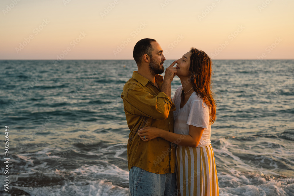 Young romantic couple dancing turning around by sea. Seascape at sunset with beautiful sky. Romantic couple on the beach at golden sunset. Lover couple having fun on beach.