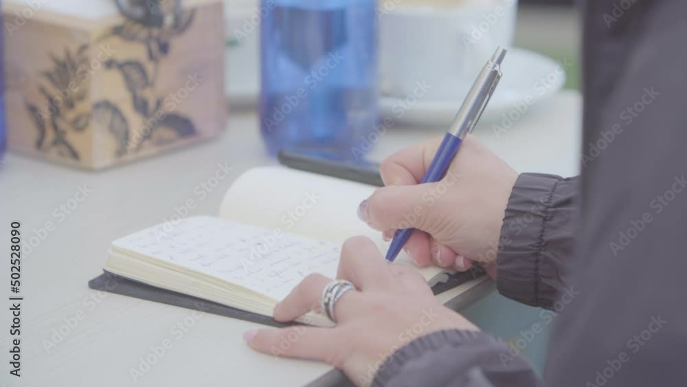 Close up of a business woman's hands taking notes on paper. Training workshop on the terrace