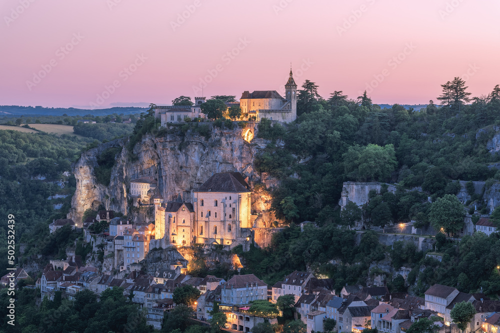 Twilight approaches Rocamadour and first warm  light from illumination appears on the sacred places of ancient village. Lot, Occitania, Southwestern France