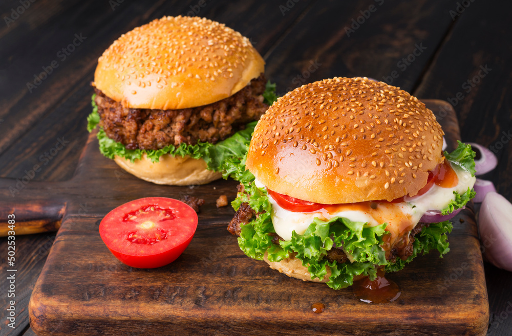 Close-up of delicious homemade burgers on a black wooden table. Delicious freshly prepared chicken, pork, or beef hamburgers. Close-up of delicious homemade burgers on a black wooden table. Delicious freshly prepared chicken, pork, or beef hamburgers.