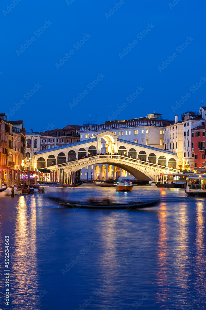 Venice Rialto bridge over Canal Grande with gondola travel traveling holidays vacation town portrait format at night in Italy