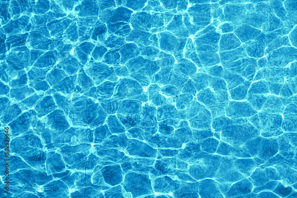 Water in fountain or pool shimmering in the sun. Rippling water surface with sun glare.