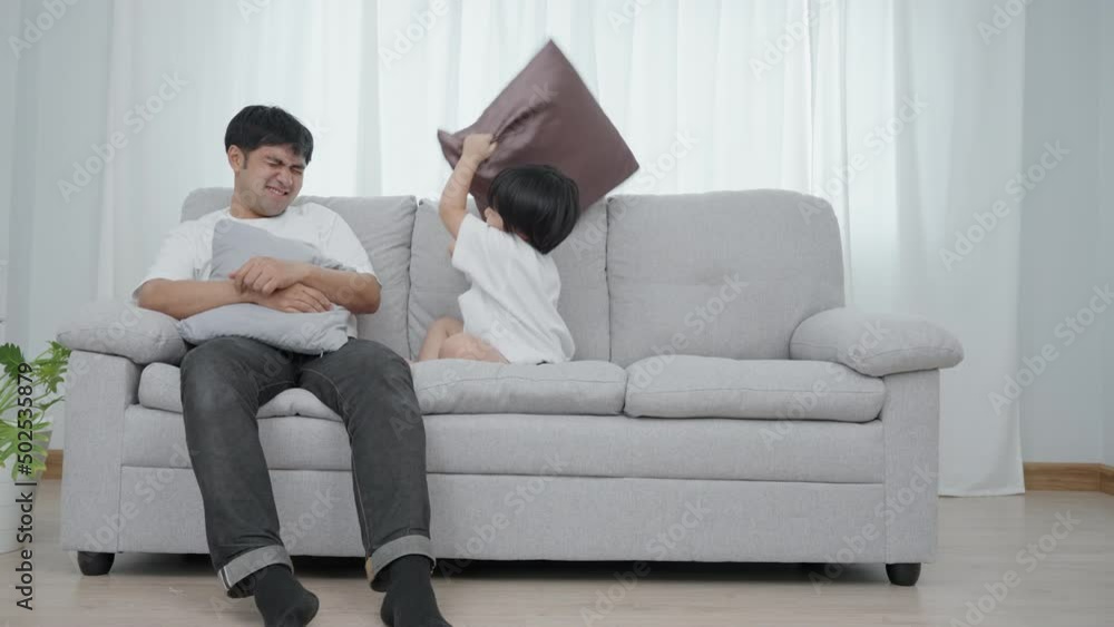 Father and son are having activity on the weekend. The son was playing with his father on the sofa in the new house he had moved in. Family on new house concept. Father and son are having activity on the weekend. The son was playing with his father on the sofa in the new house he had moved in. Family on new house concept.