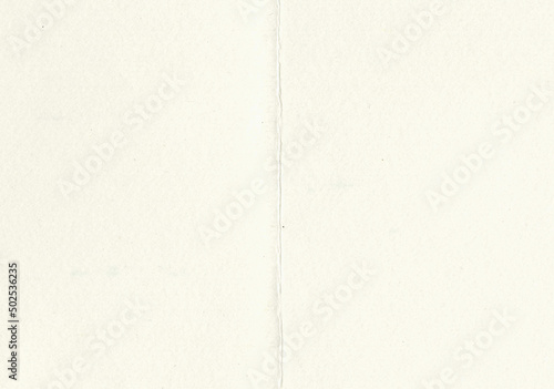 Large image of close up paper texture background folded in half with aged, uncoated fine fiber grain and dust particles in light beige yellowed color smooth with copy space for text wallpaper designs
