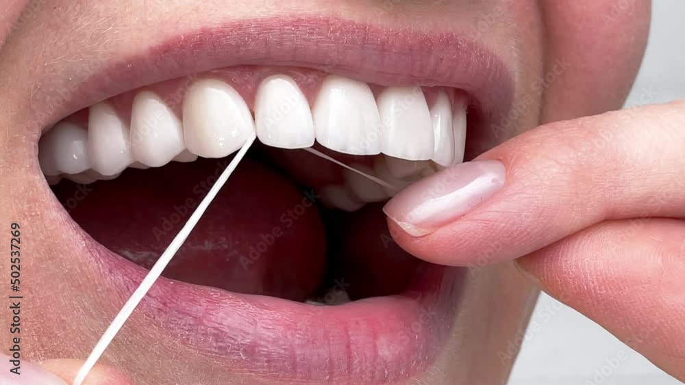 Closeup woman flossing perfect white teeth with floss toothcare hygiene
