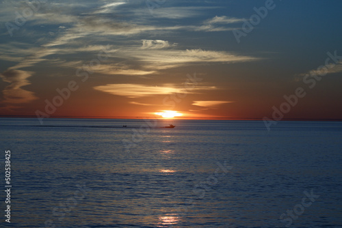 sunset over the ocean with boat in the distance. © Andy