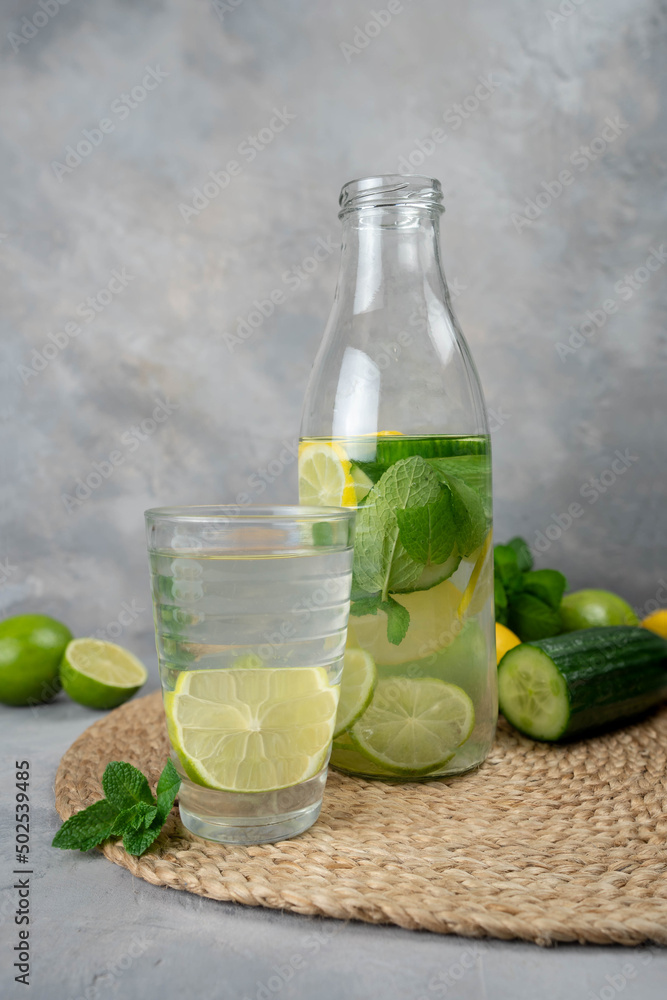 Detox Sassy water with lemon, cucumber, mint. A bottle of clean, cool and fresh drink stands on a gray concrete background with ingredients on board. Strengthening immunity, diet. Detox Sassy water with lemon, cucumber, mint. A bottle of clean, cool and fresh drink stands on a gray concrete background with ingredients on board. Strengthening immunity, diet.