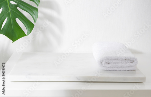 Foto Folded spa towel on white marble podium for product display