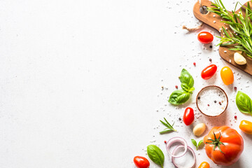 Ingredients for cooking on white stone table. Vegetables, herbs and spices with wooden cutting board. Top view with space for text.