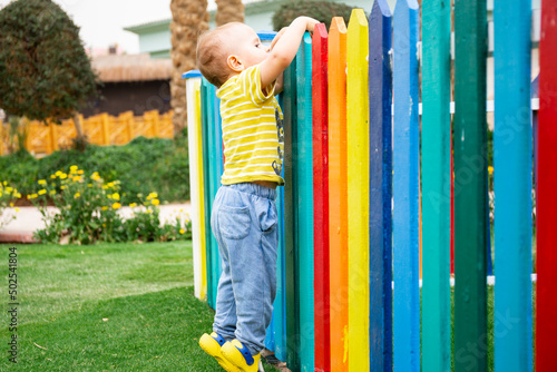 boy peeking over colorful wooden fence  of the kids club in summer resort in Egypt. Holiday concept.