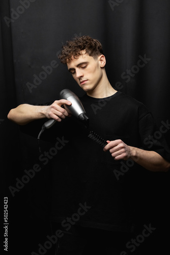 handsome barber bw portrait studio. Hair dryer and comb in barber's hands
