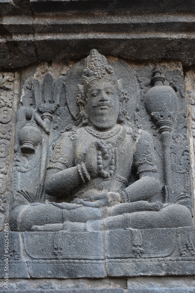 ancient buddha statue - stone carving on the walls of the temple of Prambanan near Yogyakarta, Central Java, Indonesia