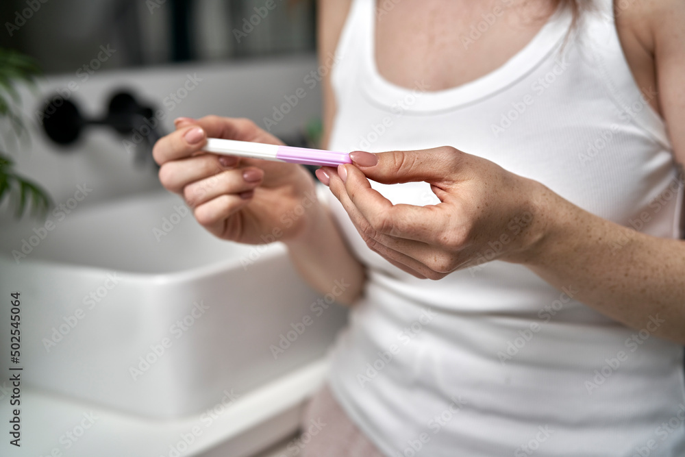 Caucasian woman in domestic bathroom looking at pregnancy test Caucasian woman in domestic bathroom looking at pregnancy test