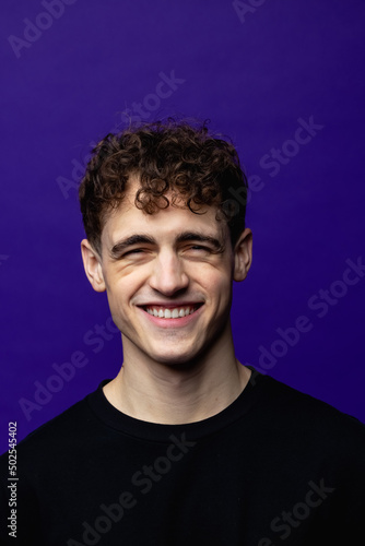 Photo of charming young happy man smile good mood wear black t-shirt isolated on purple color background