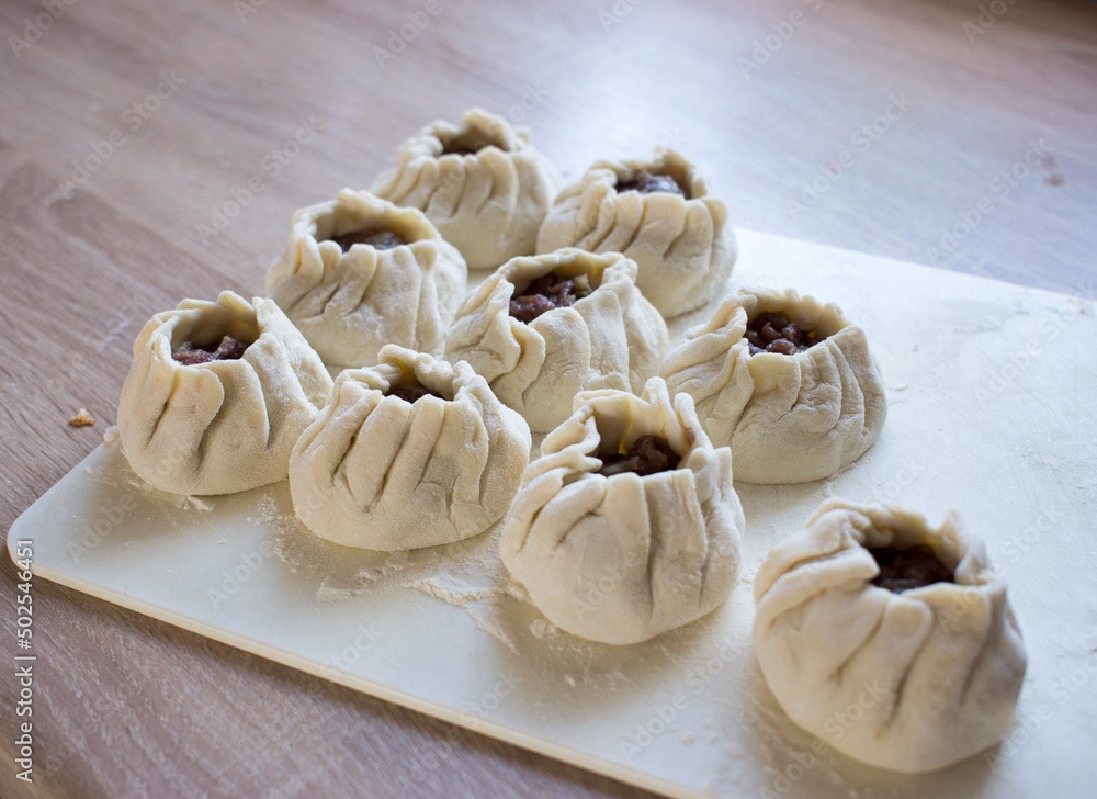 The process of making home-made dumplings. Raw homemade dumplings on a wooden board. Molding dumplings.