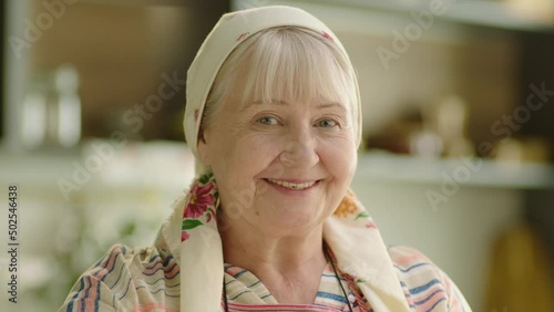 Portrait of babushka senior woman cooking and smiling at the kitchen