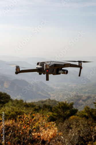 Folding small drone is flying over the mountains.