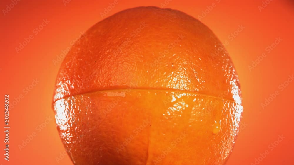 Half Orange falling and splashing on orange background. Food levitation concept. Slow Motion