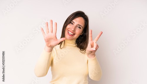 young adult pretty woman smiling and looking friendly, showing number seven or seventh with hand forward, counting down photo