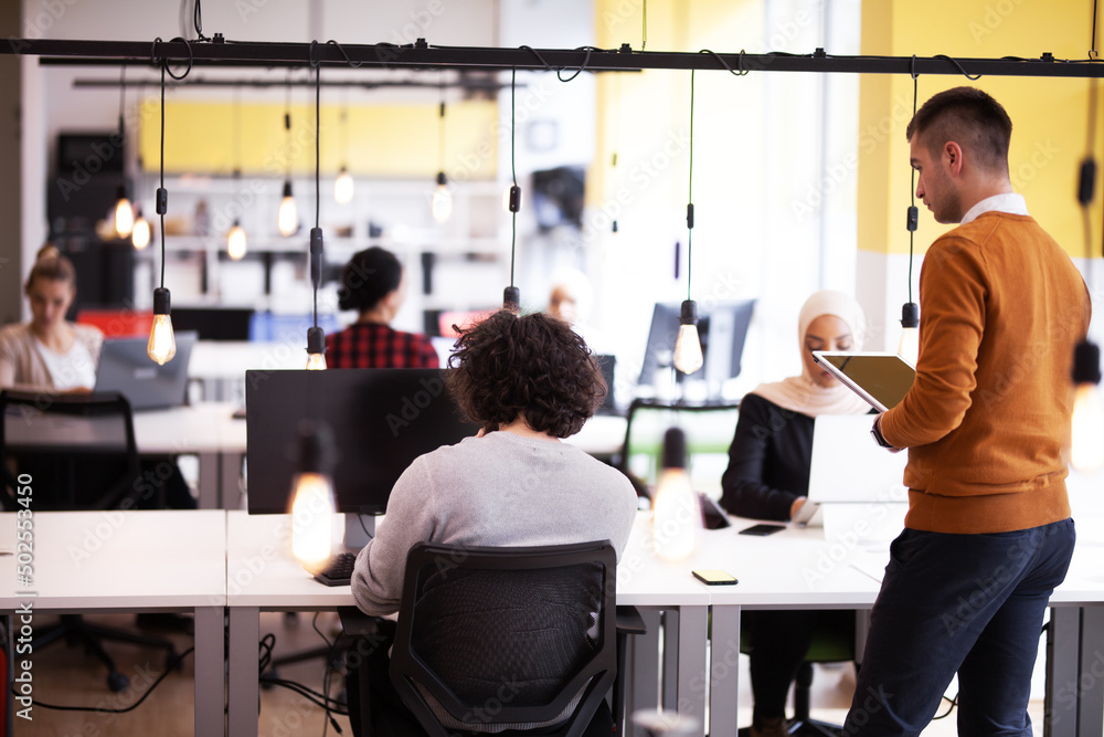 Business people having conversation in front of a computer. Modern multiethnic coworking office space. Business people having conversation in front of a computer. Modern multiethnic coworking office space.