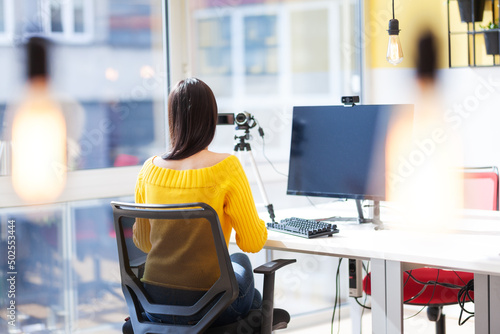 Beautiful girl talking in front of a camera recording herself. Video blogger vlogger influencer in a modern coworking space. Successful businesswoman in a modern coworking office space. photo