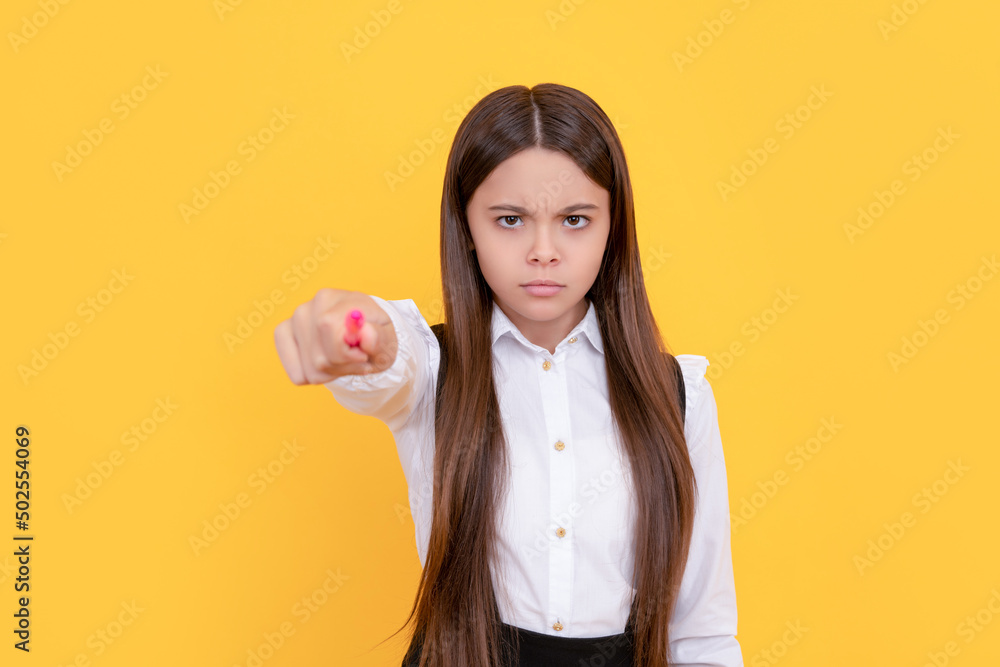 Serious frown school girl point pen putting out hand yellow background, back to school Serious frown school girl point pen putting out hand yellow background, back to school
