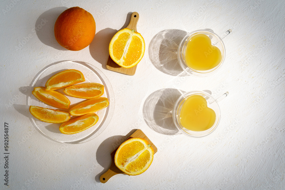 Fresh orange juice in glass with leaves, sliced oranges and ice on white background. Top view Fresh orange juice in glass with leaves, sliced oranges and ice on white background. Top view