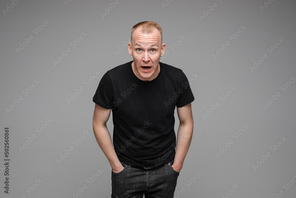 caucasian man with short fair hair wearing a black t-shirt and jeans is angry tries to explain something caucasian man with short fair hair wearing a black t-shirt and jeans is angry tries to explain something