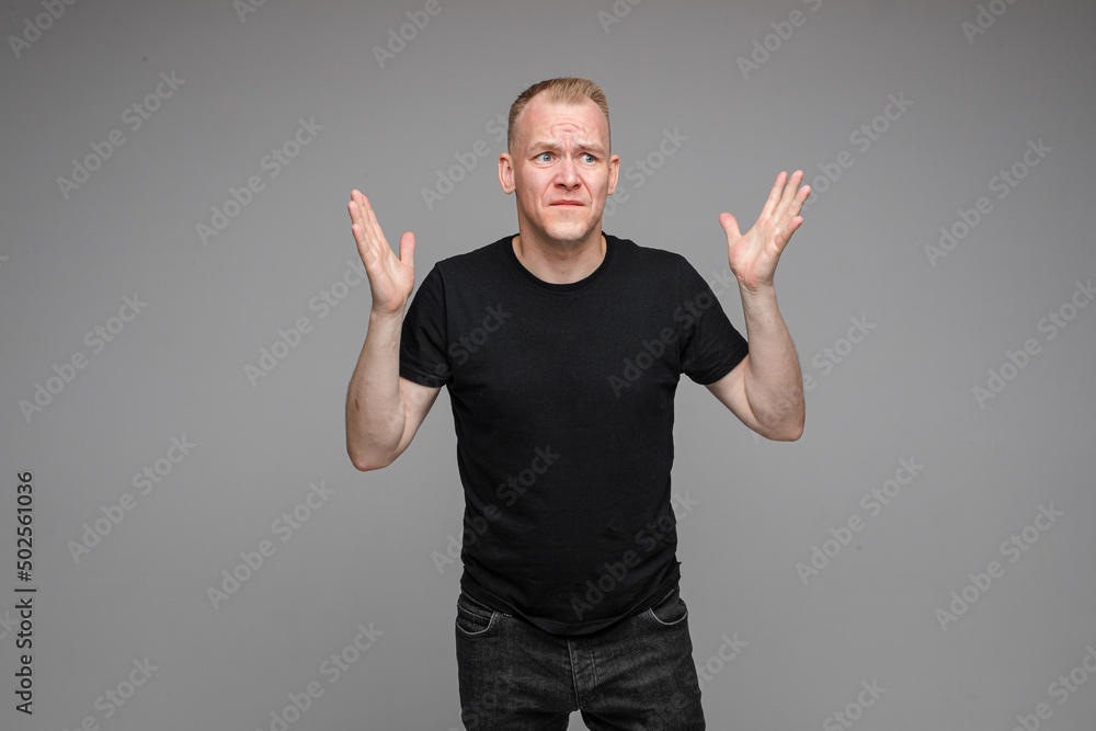 angry man with short fair hair spread his hands to the sides and rages angry man with short fair hair spread his hands to the sides and rages