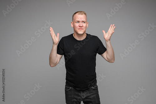 angry man with short fair hair spread his hands to the sides and rages